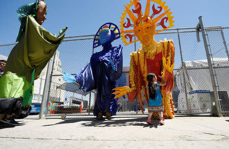 A girl high fives Sun, Moon and Tree puppets after they marched from the intersection of Florence and Normandie Avenue, the flashpoint where the riots started 25 years ago, to remember and honor the victims of the 1992 Los Angeles riots in Los Angeles, California, U.S., April 29, 2017. REUTERS/Kevork Djansezian