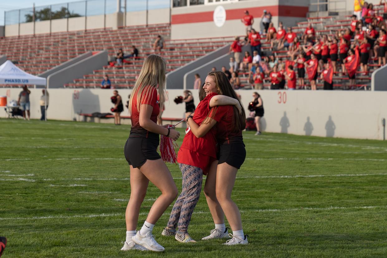 A girl hugs a Port Huron volleyball player after scoring a touchdown during Victory Day at Memorial Stadium in Port Huron on Friday, Aug. 12, 2022.