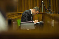 Oscar Pistorius writes notes as he sits in the dock during his trial in court in Pretoria, South Africa, Thursday, March 13, 2014. Pistorius is charged with the shooting death of his girlfriend Reeva Steenkamp on Valentine's Day in 2013. (AP Photo/Alet Pretorius, Pool)