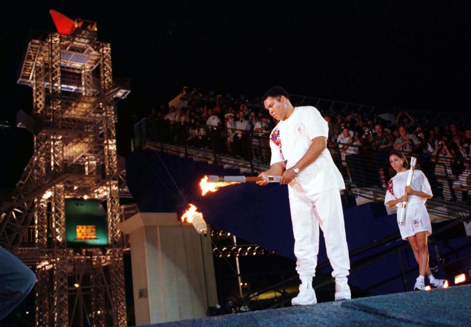 Former Olympic boxer Muhammad Ali lights the device which in turn will light the Olympic cauldron to cap the opening ceremonies of the 1996 Summer Olympics in Atlanta July 19. USA swimmer Janet Evans (R) watches after handing Ali the torch.