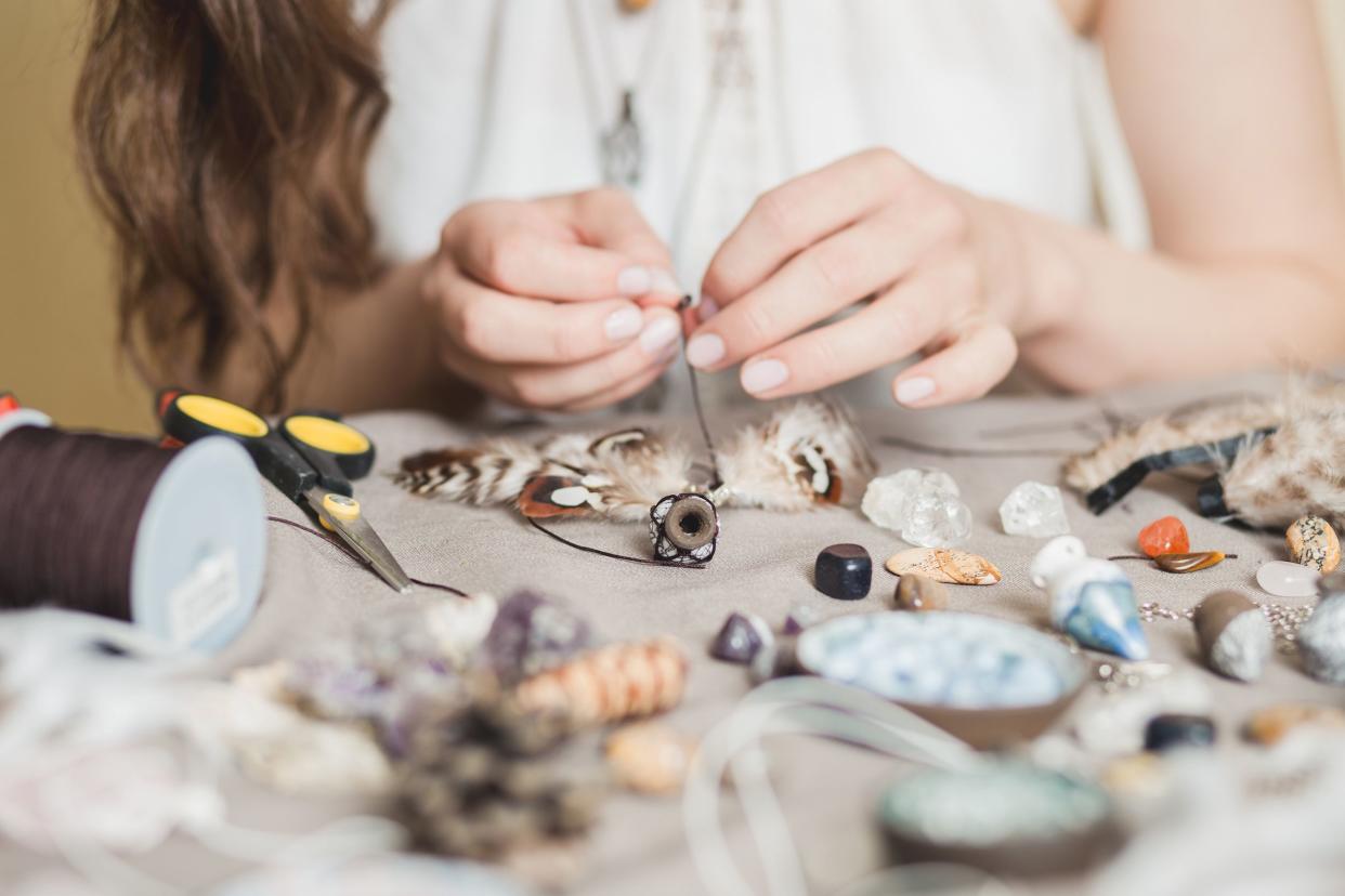 woman making trendy craft jewelry with rocks, feathers, and crystals