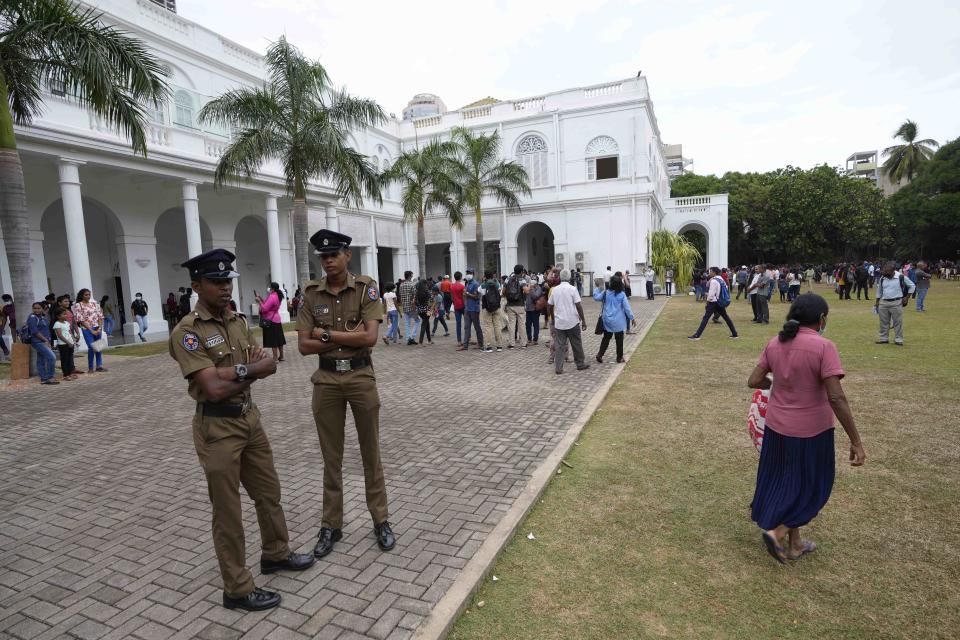 Police officers stand by the lawn as people throng President Gotabaya Rajapaksa's official residence on the second day after it was stormed in Colombo, Sri Lanka, Monday, July 11, 2022. Sri Lanka is in a political vacuum for a second day Monday with opposition leaders yet to agree on who should replace its roundly rejected leaders, whose residences are occupied by protesters, angry over the country's economic woes. (AP Photo/Eranga Jayawardena)