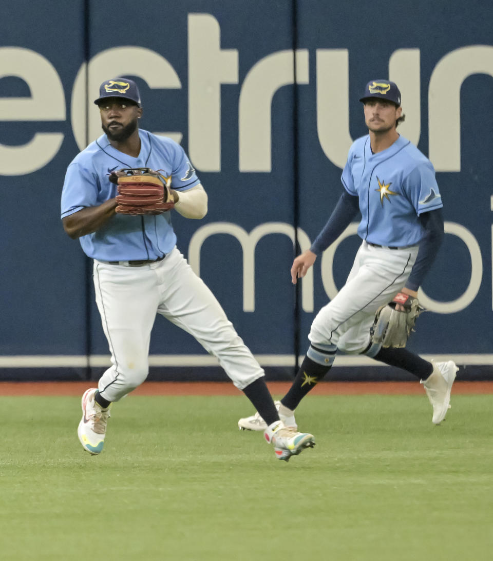 Tampa Bay Rays's Josh Lowe, right, looks on as left fielder Randy Arozarena, left, sets to make a throw after fielding Pittsburgh Pirates' Bryan Reynold's RBI-single during the third inning of a baseball game Sunday, June 26, 2022, in St. Petersburg, Fla. (AP Photo/Steve Nesius)