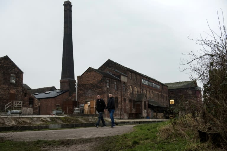 Men walk along a canal past the site of Middleport pottery, which was originally constructed in 1888, in Stoke-on-Trent, central England