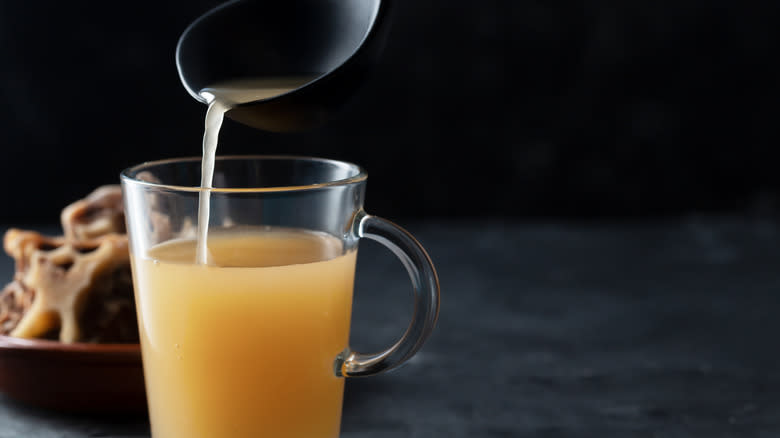 Person filling jar with bone broth