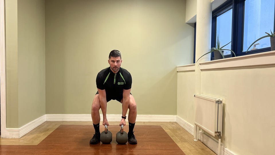 Sam Quinn, a strength coach from Nuffield Health, demonstrates a kettlebell shoulder press