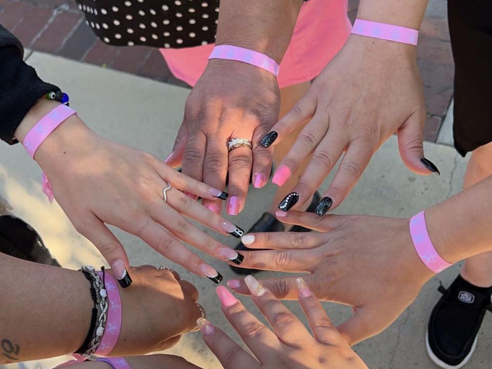 a group of people with their hands in the center wearing pink wristbands