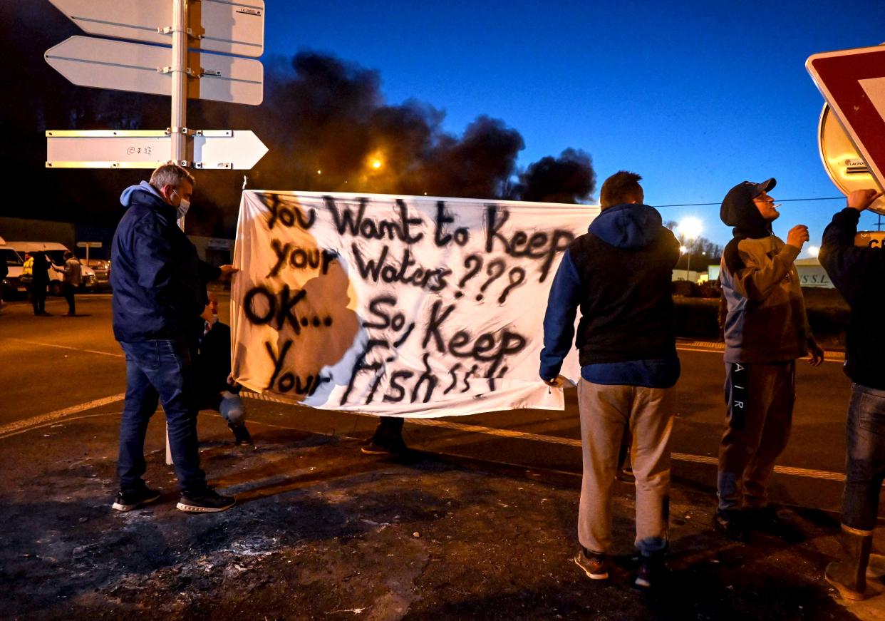 <p>French fishermen in Boulogne-sur-Mer hold a banner as they block lorries carrying UK-landed fish</p> (Reuters)