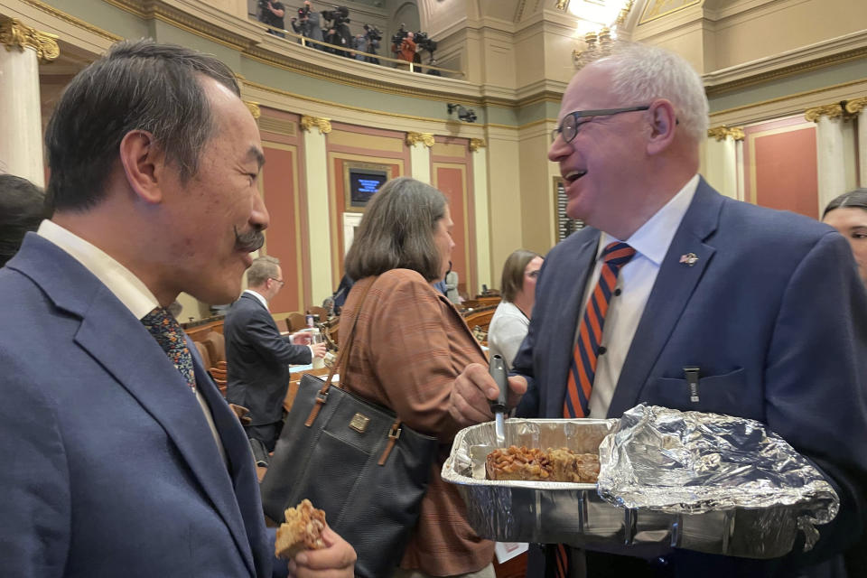 Minnesota Democratic Gov. Tim Walz serves an apple bar with caramel glaze to Rep. Ethan Cha, of Woodbury, and other state lawmakers in the state capitol building in St. Paul, Minnesota, on Feb. 12, 2024, the first day of Minnesota's legislative session for the year. Walz has a tradition of serving bars to state lawmakers each year on the first day of the legislative session in a gesture of camaraderie and bipartisanship. (AP Photo/Trisha Ahmed)