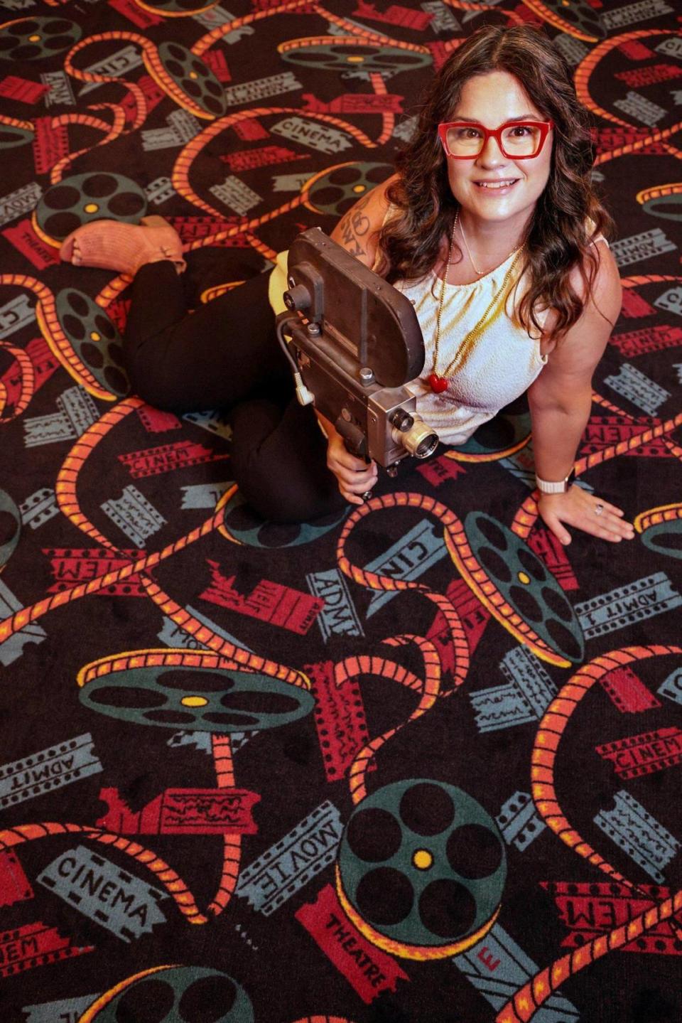 La directora ejecutiva del Coral Gables Art Cinema, Brenda Moe, se sienta en la nueva alfombra del vestíbulo. La alfombra se instaló mientras el cine estuvo cerrado durante el confinamiento por el COVID.