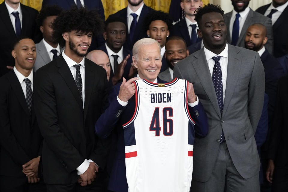 President Joe Biden is presented with a jersey by Connecticut guard Andre Jackson, Jr., left, and Connecticut forward Adama Sanogo during an event to celebrate the University of Connecticut Huskies men's basketball team's 2022-2023 NCAA Championship season in the East Room of the White House in Washington, Friday, May 26, 2023. (AP Photo/Susan Walsh)