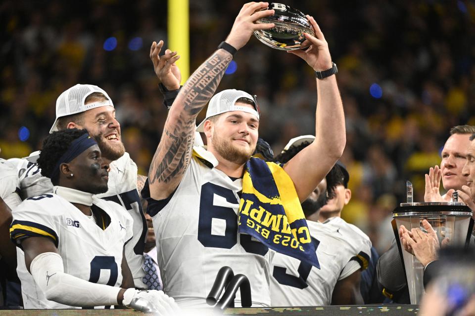 Michigan offensive lineman Zak Zinter celebrates with the trophy after winning the Big Ten Championship game against Iowa, Dec 2, 2023, in Indianapolis.