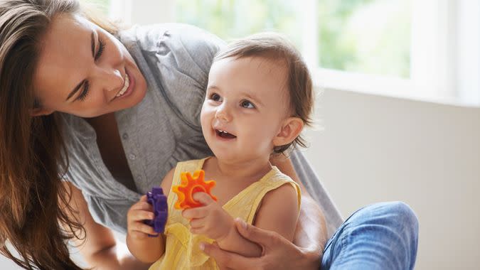 Shot of a cute baby girl sitting on the floor with her mom and playing with toys.