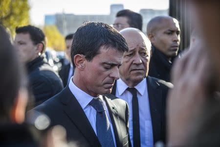 French Prime Minister Manuel Valls (L) and French Defense Minister Jean-Yves Le Drian react as they speak to journalists after they visited the psychological help center at the Ecole Militaire to assist survivors and the families of victims in Paris, France, November 15, 2015, two days after a series of fatal shootings in the French capital. REUTERS/Christophe Petit Tesson/Pool