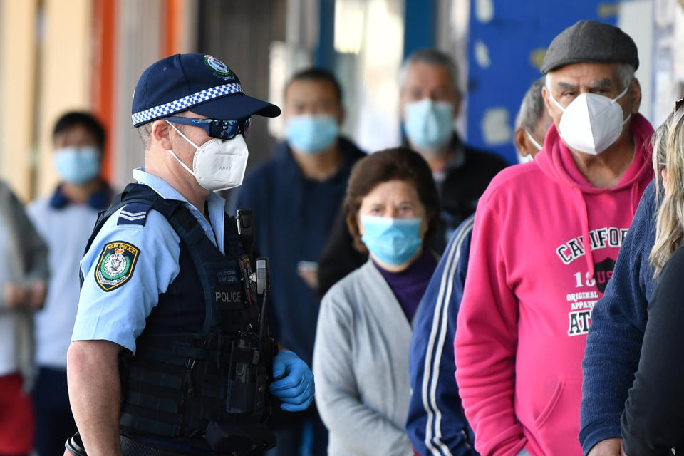 Members of the public wearing face masks wait outside a bank at Campsie in Sydney. Source: AAP