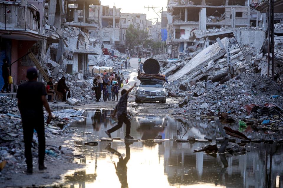 Palestinians displaced by the Israeli air and ground offensive on the Gaza Strip, walk past sewage flowing into the streets of the southern town of Khan Younis (AP)