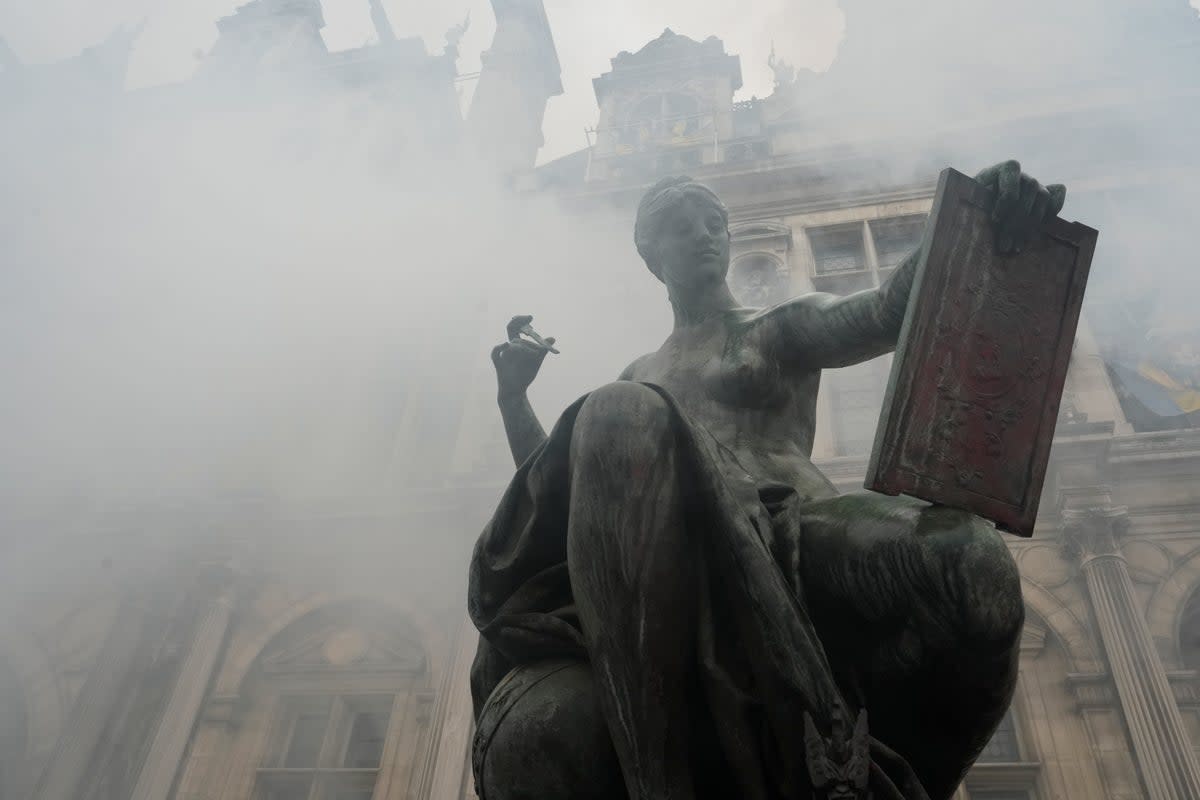 Smoke rises as demonstrators protest outside the Paris town hall (AP)