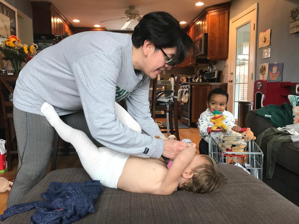 Sandra Medinilla helps daughter Remy put on a shirt as her son Theo pushes a toy cart in the background. Sandra and her wife have just adopted their fourth child.