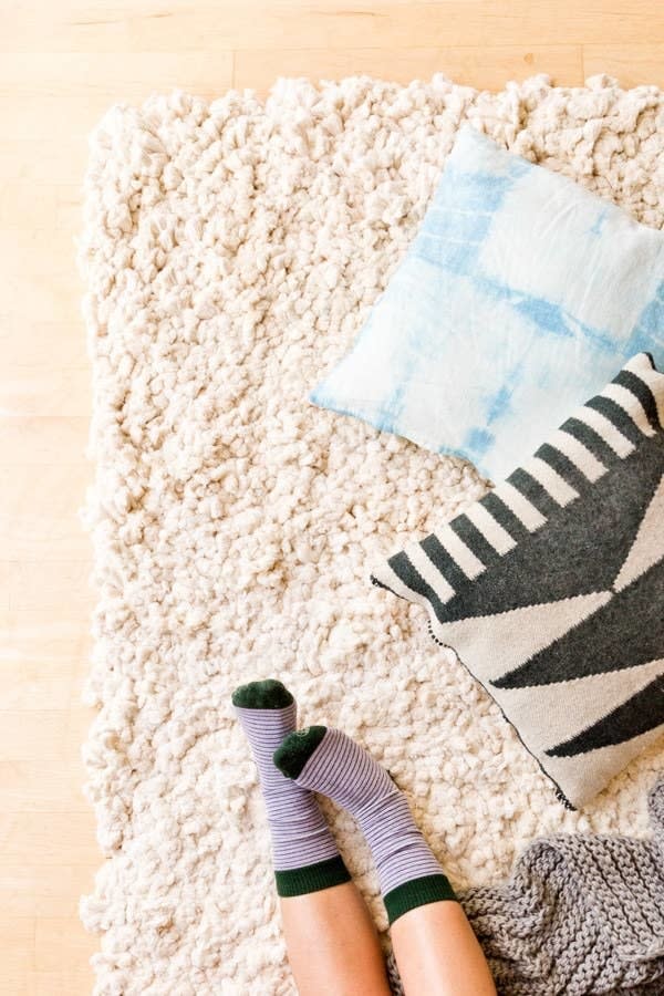 feet on a rug with pillows and a blanket