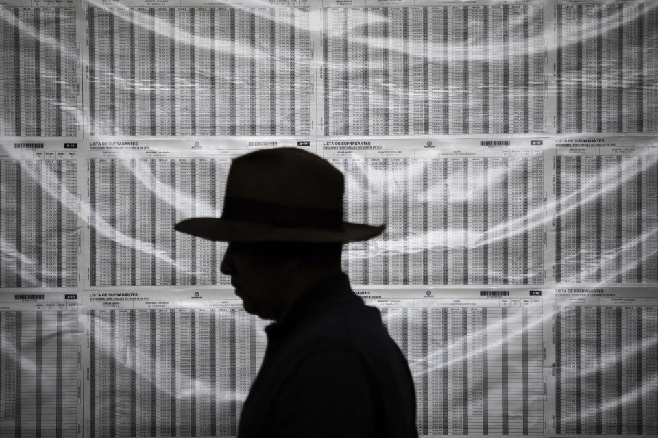 A voter walks past electoral lists during regional and local elections in Bogota, Colombia, Sunday, Oct. 29, 2023. (AP Photo/Ivan Valencia)