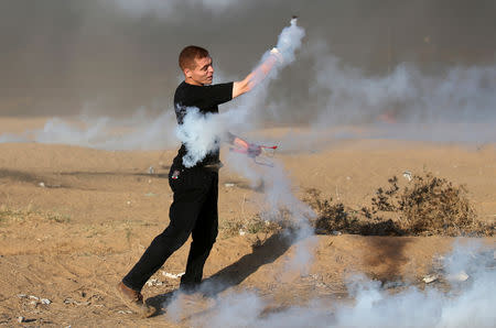 A Palestinian returns a tear gas canister fired by Israeli troops during a protest calling for lifting the Israeli blockade on Gaza and demanding the right to return to their homeland, at the Israel-Gaza border fence, in the southern Gaza Strip September 21, 2018. REUTERS/Ibraheem Abu Mustafa