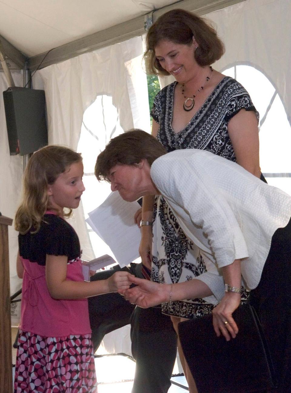 Dr. Sally Ride, who visited Goddard Space Flight Center for a tour and speech, greets a young fan on the stage with Dr. Laurie Leshin in the background.