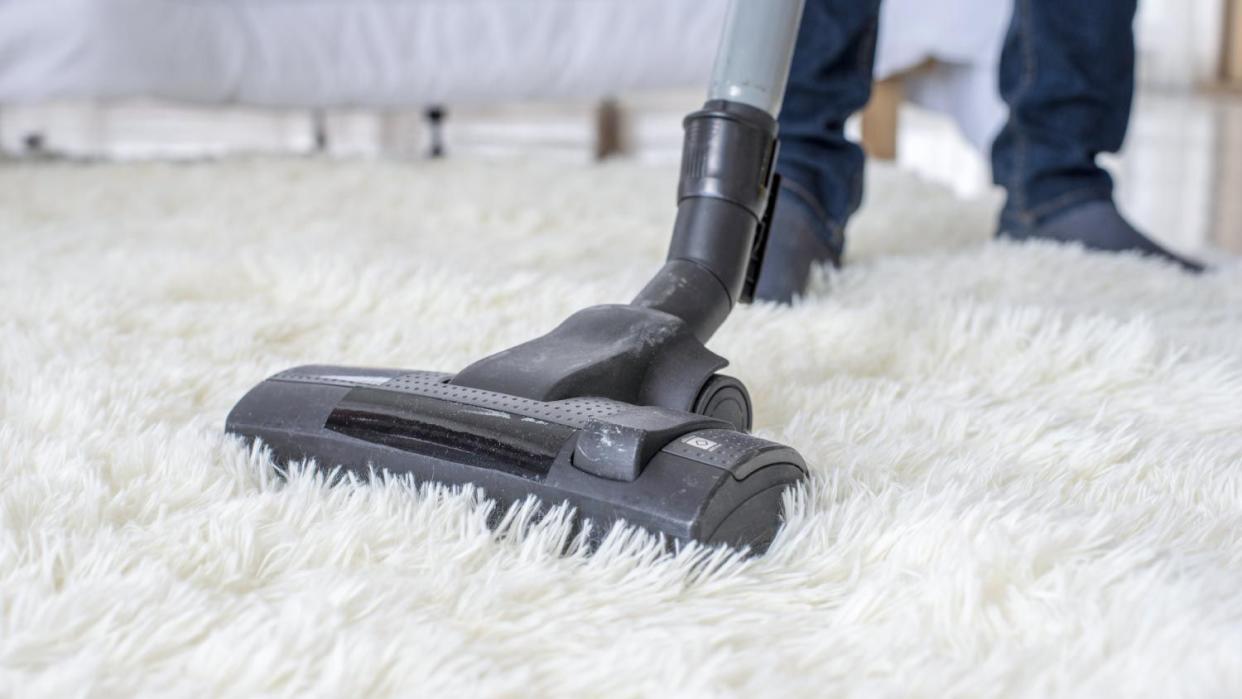 A man vacuuming on a carpet