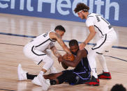 Orlando Magic's Gary Clark, center, fights for the ball against Brooklyn Nets' Chris Chiozza, left, and Tyler Johnson (8) during the first half of an NBA basketball game Tuesday, Aug. 11, 2020, in Lake Buena Vista, Fla. (Mike Ehrmann/Pool Photo via AP)