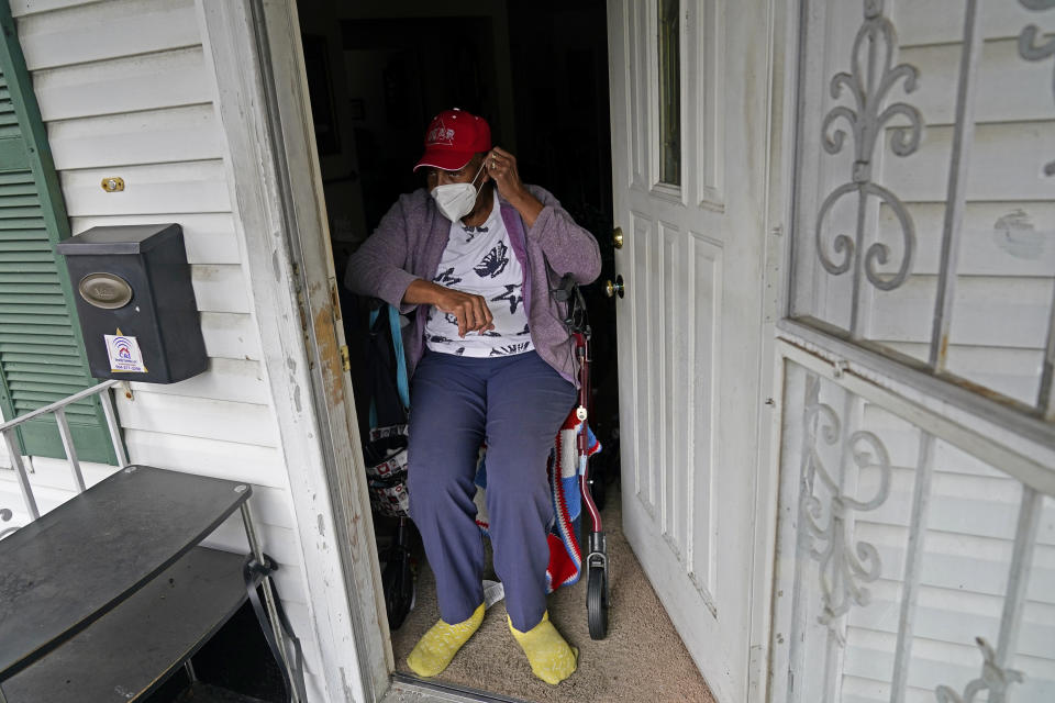 Helen Green puts on her face mask as a box of meals is delivered by Revolution Foods in New Orleans on Thursday, Feb. 11, 2021. Green, 76, must use a walker to get around and depended on her 96-year-old mother to cook for both of them before the older woman fell and went to an assisted living facility. "I'm very thankful for these meals. It makes a big difference in your life, you know," she said. (AP Photo/Gerald Herbert)