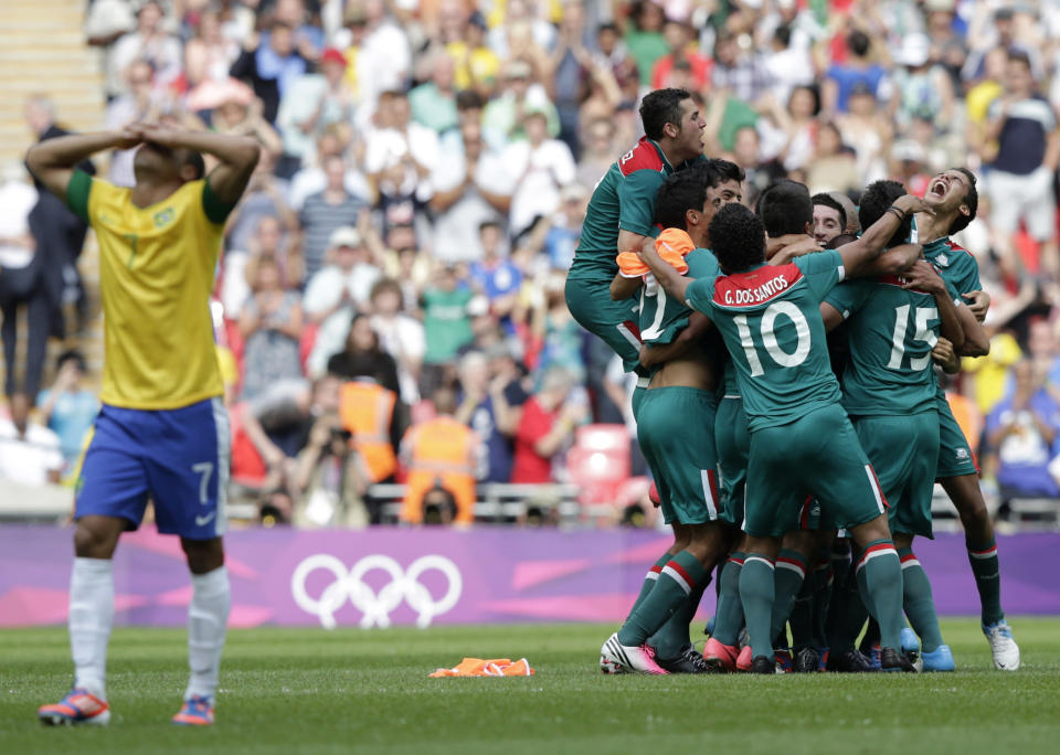 Brazil's Lucas (L) reacts as Mexico's players celebrate their victory over Brazil after their men's soccer final gold medal match at Wembley Stadium during the London 2012 Olympic Games August 11, 2012. REUTERS/Toru Hanai (BRITAIN - Tags: SPORT SOCCER OLYMPICS TPX IMAGES OF THE DAY)