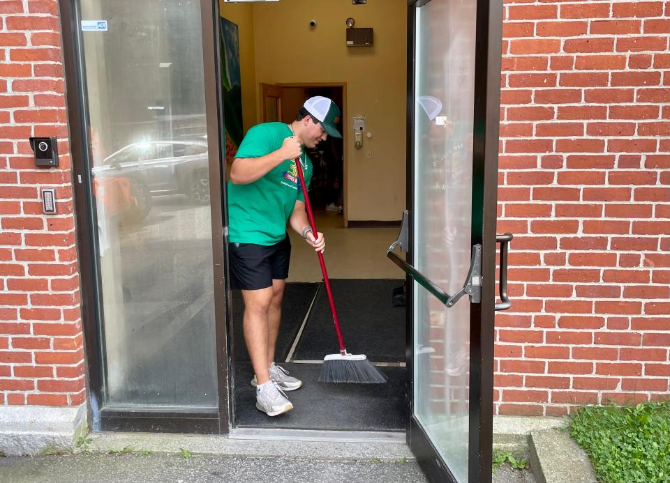 Holy Cross senior Jack Ambrosino sweeps a doorway at Belmont A.M.E. Zion Church, part of the annual Day of Caring in Worcester.