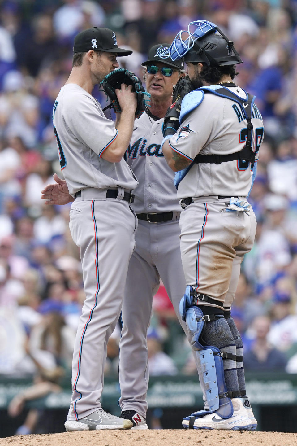 Miami Marlins manager Don Mattingly, center, talks with relief pitcher Anthony Bender, left, and catcher Jorge Alfaro during the fifth inning of a baseball game against the Chicago Cubs in Chicago, Sunday, June 20, 2021. (AP Photo/Nam Y. Huh)