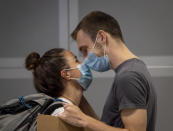 A young man welcomes his girl friend arriving from Singapore at the airport in Frankfurt, Germany, Saturday, Aug. 8, 2020. From Saturday on Covid-19 tests are mandatory for passengers coming from a high-risk-country. (AP Photo/Michael Probst)