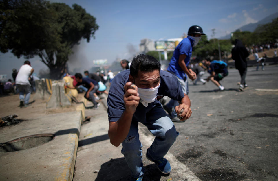 An opposition demonstrator crouches down, holding rocks, on a street near the Generalisimo Francisco de Miranda Airbase "La Carlota" in Caracas, Venezuela April 30, 2019. (Photo: Ueslei Marcelino/Reuters)