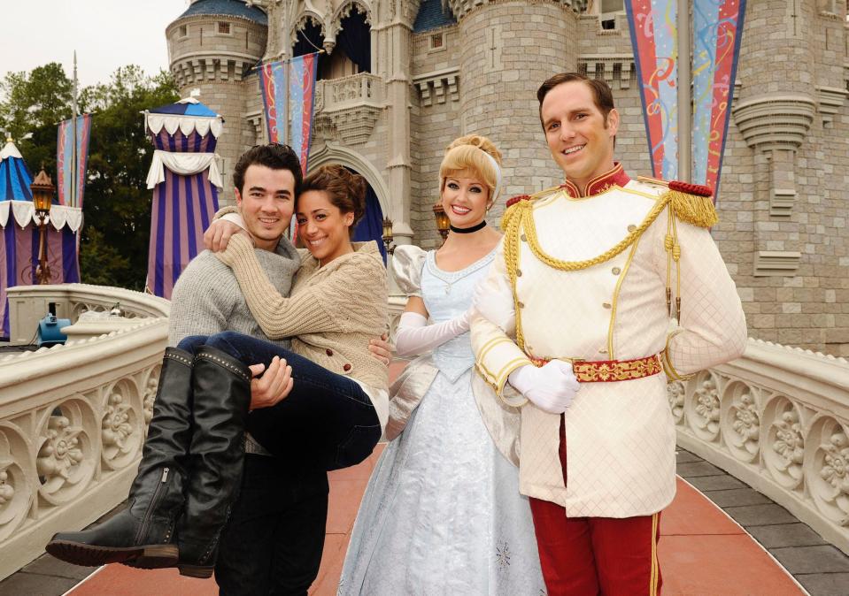 Kevin Jonas and Danielle Jonas pose with Cinderella and Prince Charming at Disney World.