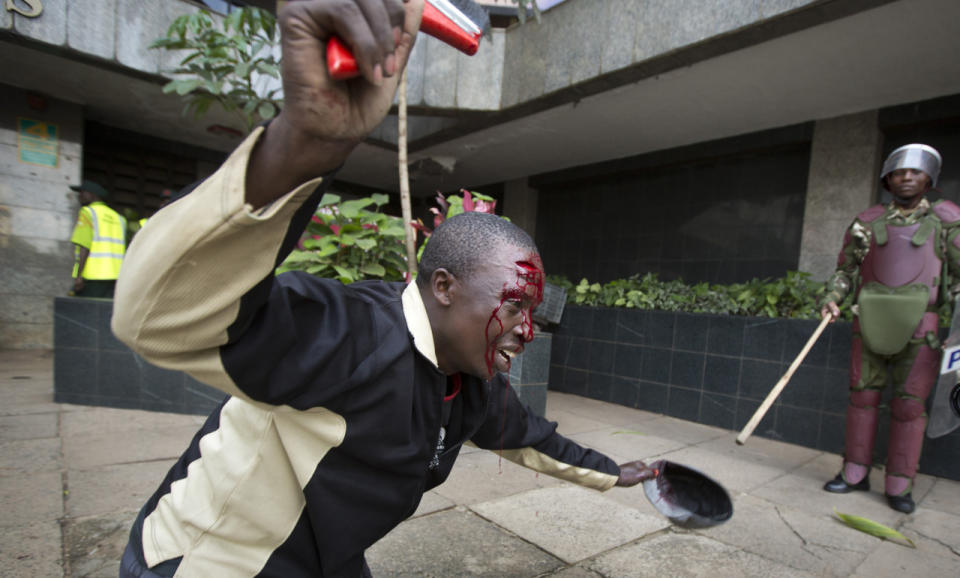 An opposition supporter with a head wound crawls past riot police, begging them not to beat him, during a protest in downtown Nairobi, Kenya, May 16, 2016. Kenyan police have tear-gassed and beaten opposition supporters during a protest demanding the disbandment of the electoral authority over alleged bias and corruption. (AP Photo/Ben Curtis)
