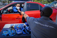 In this Wednesday, May 6, 2020, photo, Brandon Earl, right, helps David Lenus, a job seeker, fill out an application at a drive up job fair for Allied Universal during the coronavirus pandemic, in Gardena, Calif. (AP Photo/Chris Carlson)