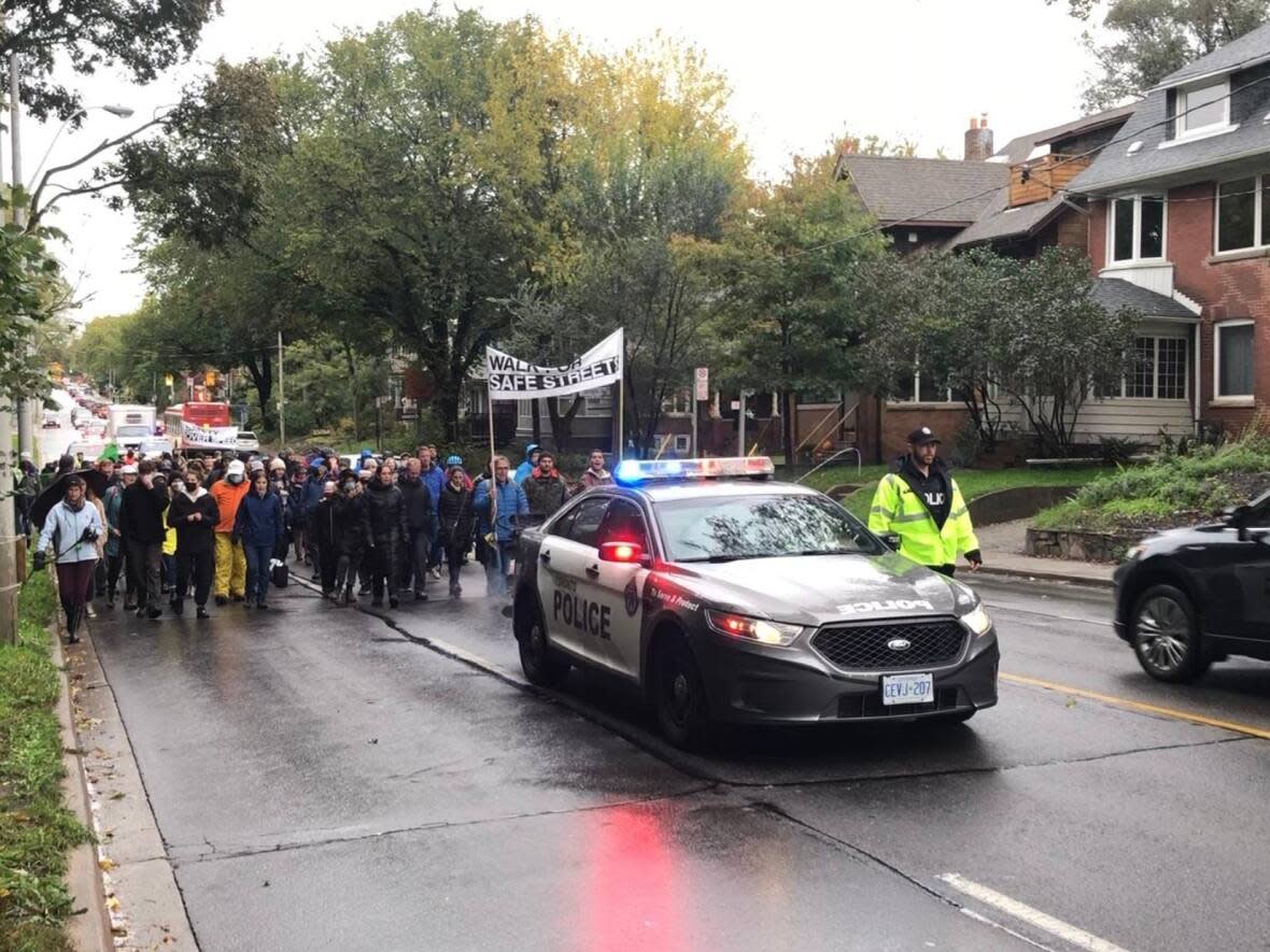 Marchers advocating for safer streets make their way down Parkside Drive in Toronto's west end on Tuesday afternoon. (DaleManucdoc/CBC - image credit)