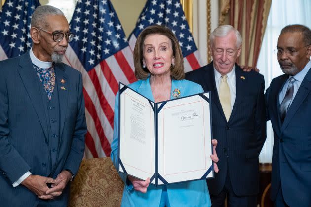 Then-House Speaker Nancy Pelosi is photographed holding up bill, the 