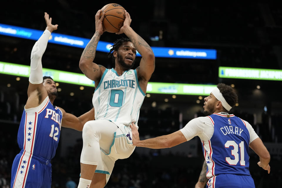 Charlotte Hornets forward Miles Bridges passes between Philadelphia 76ers forward Tobias Harris, left, and guard Seth Curry during the first half of an NBA basketball game on Monday, Dec. 6, 2021, in Charlotte, N.C. (AP Photo/Chris Carlson)