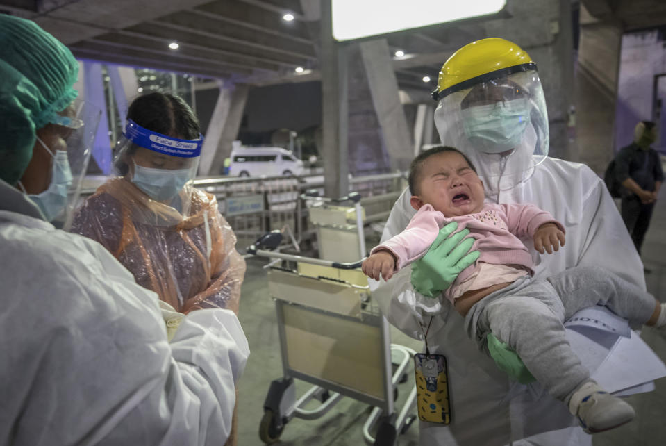 A public health worker helps Chinese tourists from Shanghai, who arrived at Suvarnabhumi airport on special tourist visas, in Bangkok, Thailand, Tuesday, Oct. 20, 2020. Thailand on Tuesday took a modest step toward reviving its coronavirus-battered tourist industry by welcoming 39 visitors who flew in from Shanghai, the first such arrival since normal traveler arrivals were banned almost seven months ago. (AP Photo/Wason Wanichakorn)