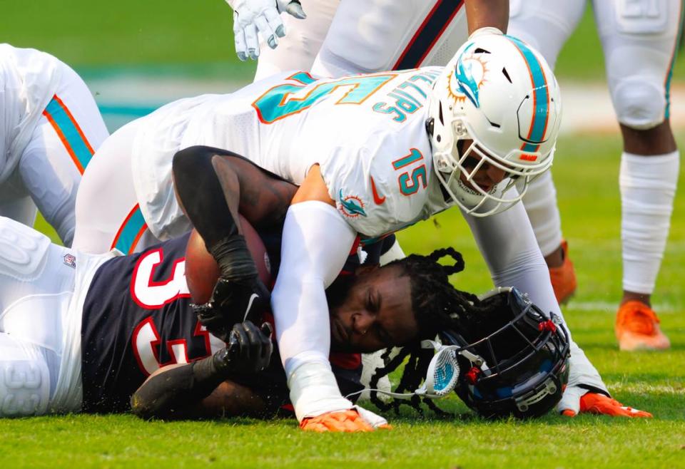 Miami Dolphins linebacker Jaelan Phillips (15) tackles Houston Texans running back Dare Ogunbowale (33) during first quarter of an NFL football game at Hard Rock Stadium on Sunday, November 27, 2022 in Miami Gardens, Florida.