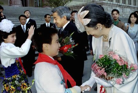 Smiling Japanese Empress Michiko shakes the hand of a Chinese boy as she and Emperor Akihito receive flower bouquets from young wellwishers during the welcoming ceremoy for the Imperial couple's historic visit to China at Beijing's Great Hall of the People, October 23. 1992. Pool via REUTERS/Files