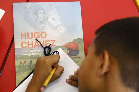 A child writes a story about the late Venezuelan President Hugo Chavez during a writing workshop at the 4F military fort in Caracas December 14, 2014. REUTERS/Carlos Garcia Rawlins