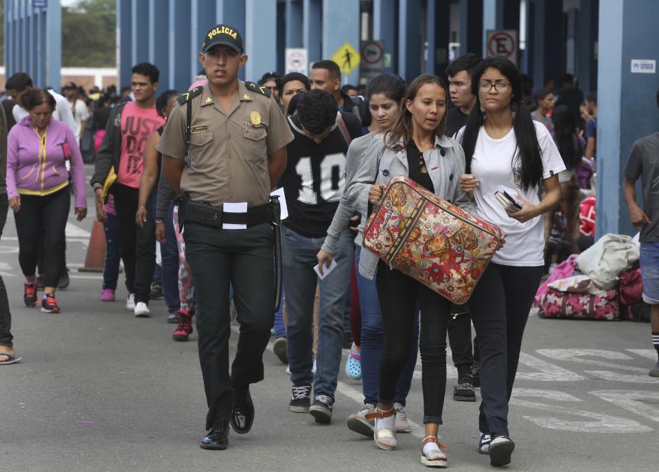 A police officer walks with Venezuelan migrants after stricter entry requirements went into effect, in Tumbes, Peru, Saturday, June 15, 2019. With its relatively stable economy and flexible immigration laws, Peru has become a main destination for millions of Venezuelans escaping hyperinflation, medical shortages and political repression at home. (AP Photo/Martin Mejia)