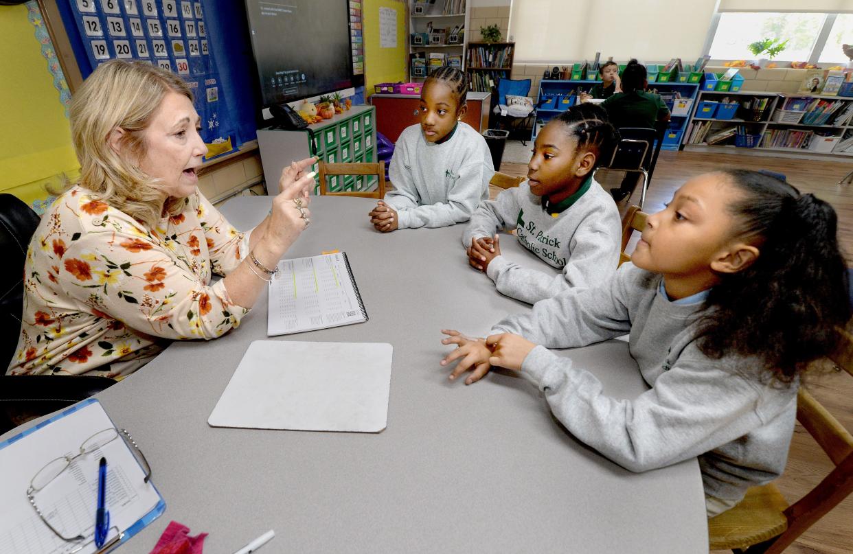 Third and fourth grad teacher at St. Patrick's Catholic School Teresa Mattsson, left, goes over a phonics lesson with some of her students, front to back, Rayne Blakey, 8, Addisyn Williams, 8, and Madisyn Renicks, 8, all of Springfield, Wednesday, Nov. 1, 2023.