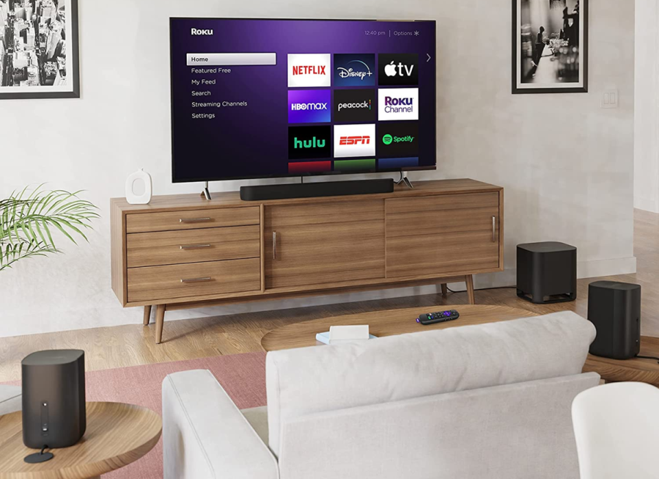 A photo of the Roku Streambar Pro bundle in a living room, with a TV showing the Roku interface.