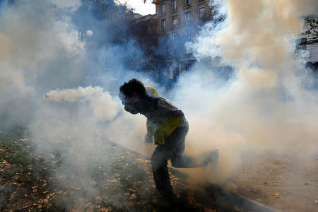 A demonstrator runs through a tear gas cloud as they clash with riot police during an unauthorized march called by secondary students to protest against government education reforms in Santiago, Chile, May 26, 2016. REUTERS/Ivan Alvarado