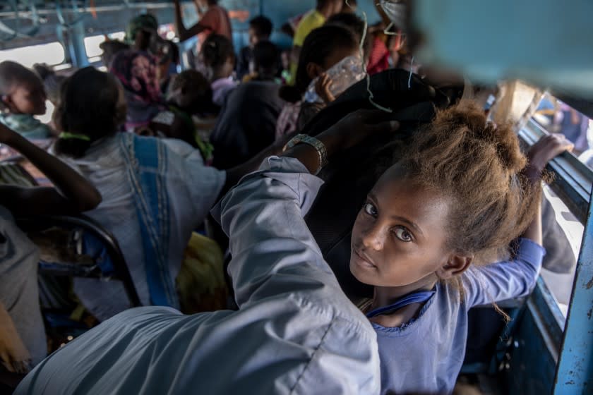 FILE - In this Dec. 1, 2020, file photo, refugees who fled the conflict in the Ethiopia's Tigray ride a bus going to the Village 8 temporary shelter, near the Sudan-Ethiopia border, in Hamdayet, eastern Sudan. In a remote part of neighboring Sudan, no coronavirus testing is taking place in the crowded camps that are now home to more than 45,000 Ethiopian refugees. People share shelters and stand close together in lines for food, cash and registration. There are few face masks to be seen. (AP Photo/Nariman El-Mofty, File)