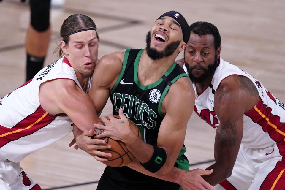 Boston Celtics forward Jayson Tatum, center, struggles to maintain control of the ball as Miami Heat forward Kelly Olynyk, left, and Andre Iguodala, right, attempt to strip it away during the first half of an NBA conference final playoff basketball game, Thursday, Sept. 17, 2020, in Lake Buena Vista, Fla. (AP Photo/Mark J. Terrill)